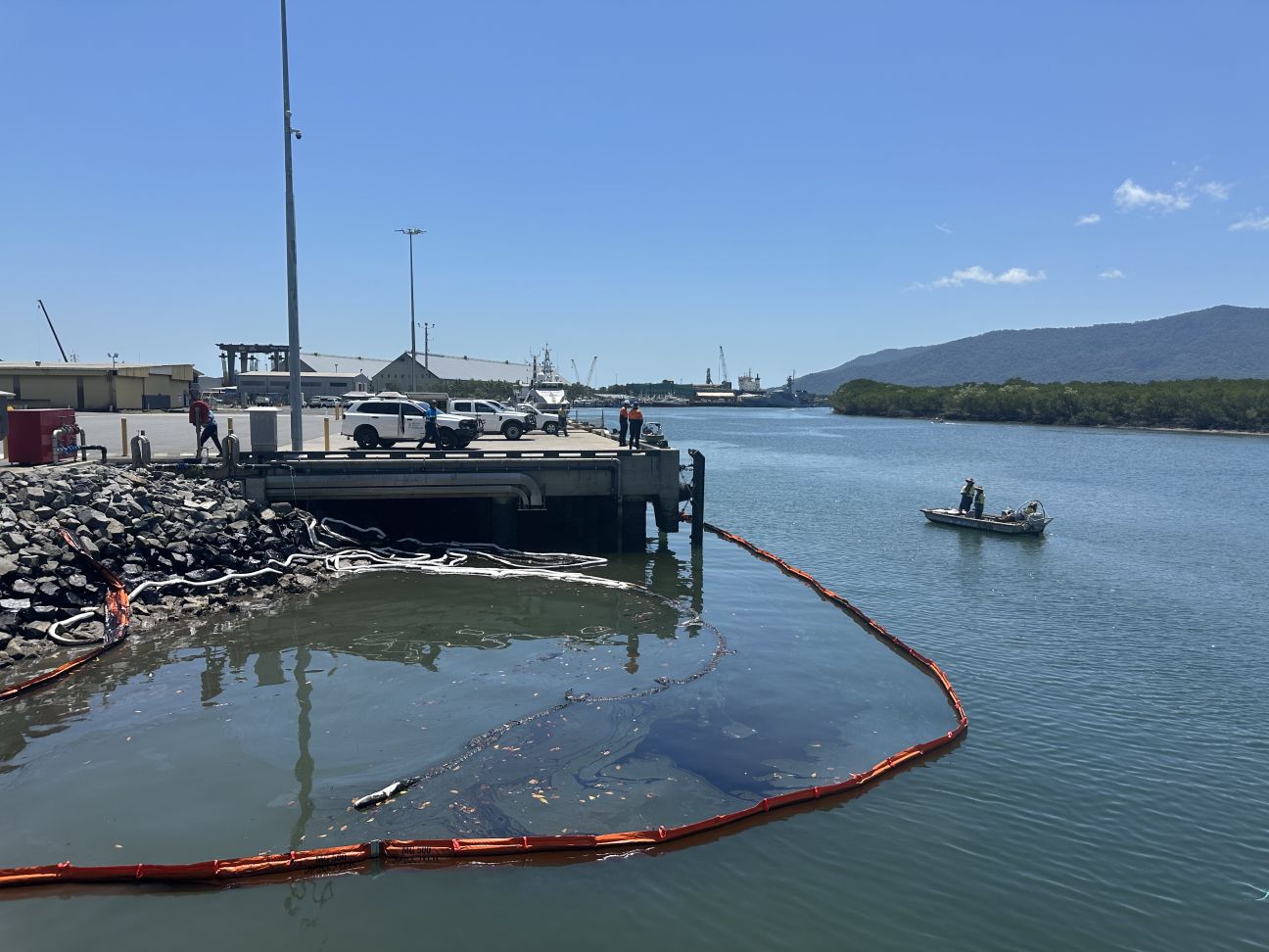 Photo of water's edge showing containment structures on the water.